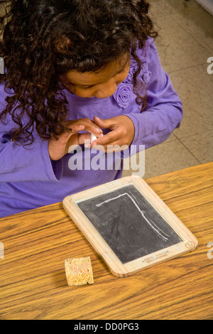 Eine sehbehinderte Mädchen versucht, einen großen Kreide Buchstaben sehen, "L" in einem speziellen schreiben Klasse Stockfoto