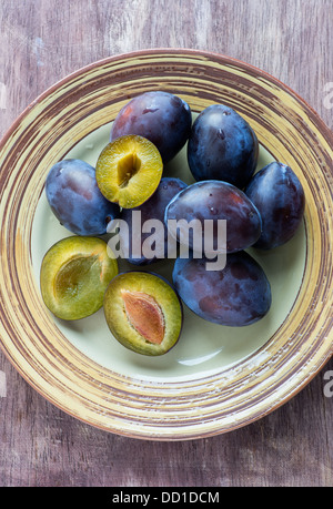 Frische Pflaumen auf Platte über hölzerne Hintergrund, über Kopf Stockfoto