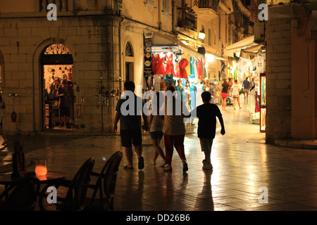 Menschen, die ein Spaziergang durch die engen Gassen Shop gesäumten Straßen in der Nacht in Korfu, Griechenland Stockfoto