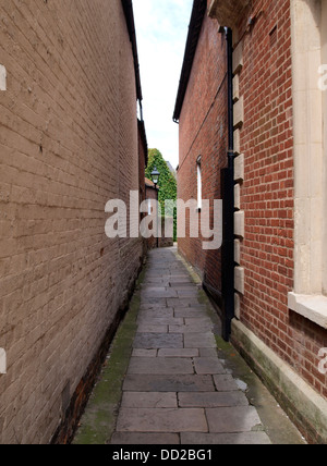 Schmale Stein gepflasterte Gasse zwischen zwei Gebäuden, Christchurch, Dorset, Großbritannien 2013 Stockfoto
