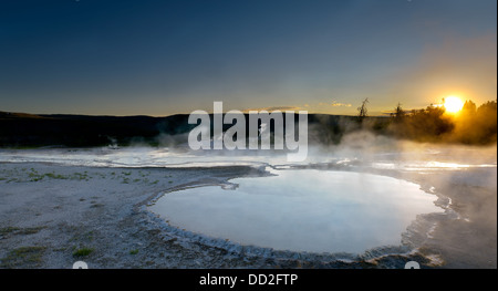 Die Sonne geht hinter die dampfende heiße Quellen rund um die Old Faithful Geysir im Yellowstone National Park, Montana. Stockfoto