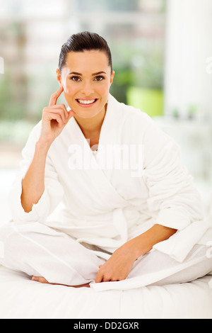 attraktive Frau mit weißen Bademantel sitzen auf Bett Stockfoto