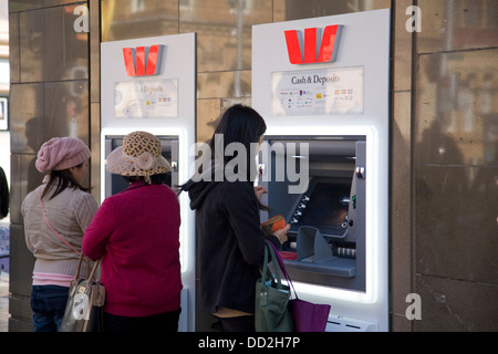 Zwei asiatische Damen, die Bargeld von einem Bankautomaten in der George Street, Sydney, NSW, Australien abheben Stockfoto