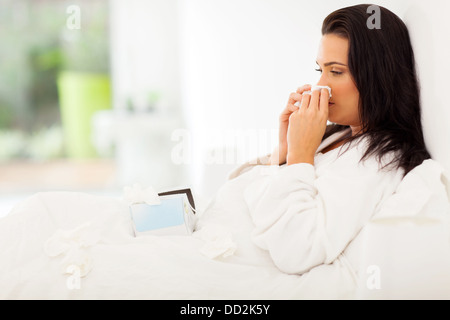 kranke Frau im Bett ihre Nase weht Stockfoto