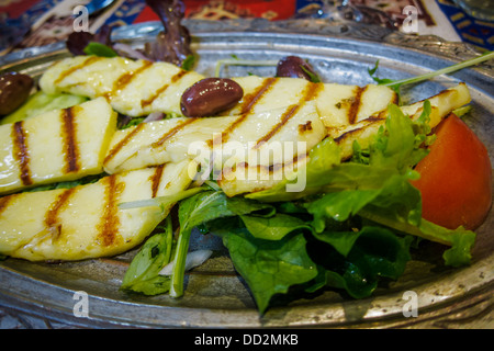 Traditionelle türkische Gerichte von gegrilltem Halloumi-Käse auf einem silbernen Tablett mit grünem Salat und Oliven Stockfoto