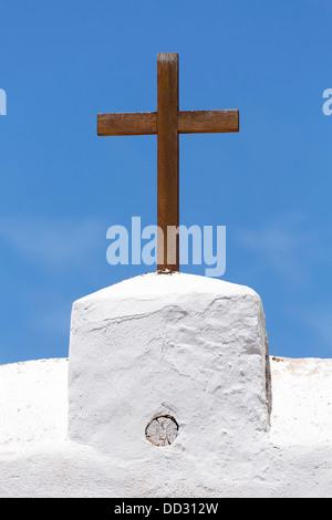 Christian Kreuz aus Holz auf eine weiße Kirche vor blauem Himmel Stockfoto