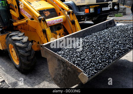 Eimer mit Radlader mit Asphalt für Straßenreparatur gefüllt Stockfoto