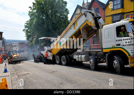 Straßenbau, asphalt Verbreitung Maschine wird geladen mit Asphalt von Muldenkipper für Straße Oberflächenersatz UK Stockfoto