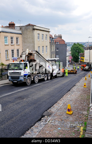 Straßenbau, asphalt Verbreitung Maschine wird geladen mit Asphalt von Muldenkipper für Straße Oberflächenersatz UK Stockfoto