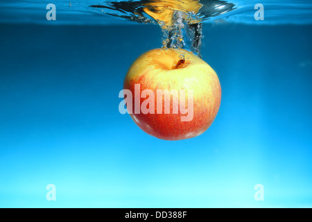 Rot, gelber Apfel im klaren, blauen Wasser. Gesunde Nutrion Konzept. Stockfoto