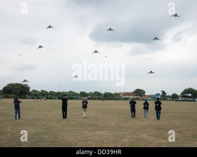 Mitglieder von einem Lenkdrachen anzeigen Team Stand in der Schlange und ihre Drachen in Abstimmung Stockfoto