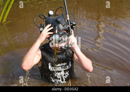 Llanwrtyd Wells, UK.25th August 2013. Australische Komiker & TV Host Amos Gill 22, tourt die Welt mit ABC-TV machen Kinder Dokumentarfilm über ungewöhnliche Ereignisse. Der jährlichen Weltmeisterschaft Bogsnorkelling findet jeden August Bank Holiday im berühmten Wän Rhydd Bog.in die Waliser der Cambrian Mountains in der Nähe von der kleinsten Stadt in Großbritannien bekannt für seine skurrilen Sport. Die Idee entstand im Jahr 1985 durch Vermieter Gordon Green The Neuadd Arms Pub Llanwrtyd Wells auf die Karte setzen. Weltmeister ist Andrew Holmes mit der Zeit der 84secs in 2011.Photo:Graham M. Lawrence/Alamy Live News Stockfoto