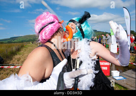 Llanwrtyd Wells, UK. 25. August 2013. Hannah Fraser (R) und Gemma Fry (L) – The Happy Flapper – beide lokale Damen Freizeit dress up für das Moor.  Der jährlichen Weltmeisterschaft Bogsnorkelling findet jeden August Bank Holiday im berühmten Wän Rhydd Bog.in die Waliser der Cambrian Mountains in der Nähe von der kleinsten Stadt in Großbritannien bekannt für seine skurrilen Sport. Die Idee entstand im Jahr 1985 durch Vermieter Gordon Green The Neuadd Arms Pub Llanwrtyd Wells auf die Karte setzen. Weltmeister ist Andrew Holmes mit einer Zeit von 84secs im Jahr 2011. Foto: Graham M. Lawrence/Alamy Live-Nachrichten. Stockfoto