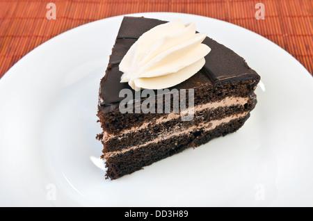 Stück Schokoladenkuchen auf weißen Teller am Tisch Stockfoto