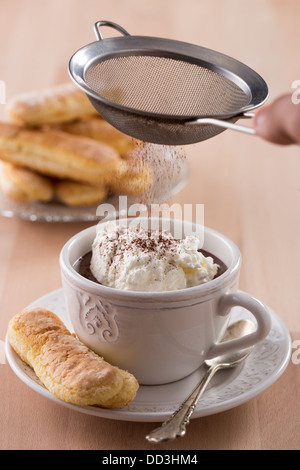 Schokolade Tasse mit Schlagsahne und Löffelbiskuits auf Holztisch Stockfoto
