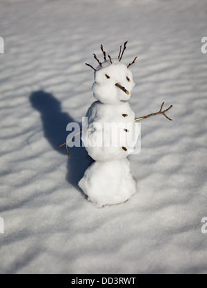 Kleine lustige Schneemann auf dem Hintergrund der Schneeverwehungen Stockfoto