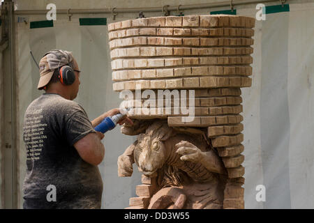 Tabley, Cheshire, UK 25 August, 2013. Steven Kenzora aus Kanada auf der 9. englischen Öffnen Chainsaw Carving Wettbewerb, Cheshire County Showground, Spiel und County Fair, Tabley, Nr Knutsford, Großbritannien. Die Kettensäge Carver Holz (manchmal riesige Bits) schönen Schnitzereien von bis zu 20 Meter hoch zu produzieren. Wenn jeder wird gesucht nach Kunstwerk holz skulptur, Sägemehl, Bildhauer, Holz, Späne, Log, professionell, arbeiten, Kunst, Künstler, Ausschneiden, Kettensäge, Kunstwerke aus grobem Holz Log gemacht. Stockfoto