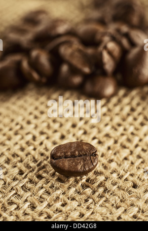 Kaffeebohne auf Jute Leinwandstruktur. Makroaufnahme. Stockfoto