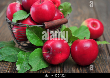 Äpfel im Metallkorb auf hölzernen Hintergrund Stockfoto