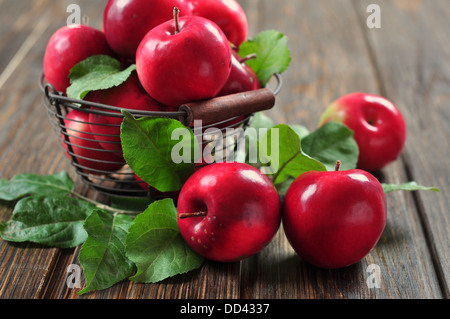 Äpfel im Metallkorb auf hölzernen Hintergrund Stockfoto