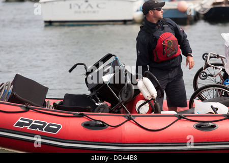 Rollstühle sind aus dem Dock zu einem anderen durch ein Schlauchboot durch den Trainer in einer behinderten Segelregatta in Rhode Island verschoben. Stockfoto