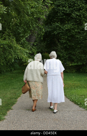 Zwei ältere Frauen gehen hand in hand von hinten gesehen. Stockfoto