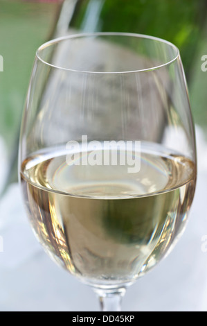 Schließen Sie die Ansicht auf Weißweinglas auf Terrasse Tisch mit Flasche und Weinkühler hinter Stockfoto