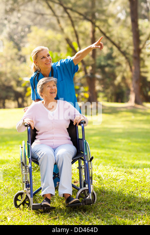 freundliche Krankenschwester unter deaktiviert älteren Patient für einen Spaziergang Stockfoto