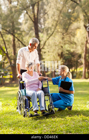 hübschen weiblichen Arzt Gruß erholt senior Patienten im Rollstuhl im freien Stockfoto