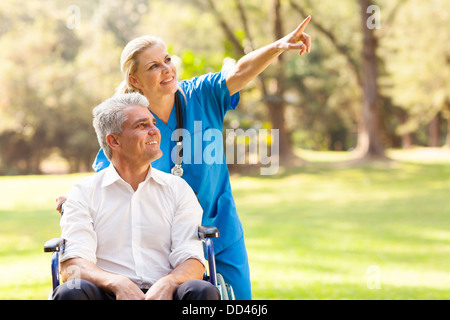 schöne Mitarbeiter nehmen behinderte Patienten für einen Spaziergang im freien Stockfoto