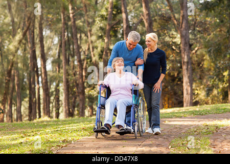 fürsorgliche paar nehmen ihre deaktivieren senior Mutter für einen Spaziergang im park Stockfoto