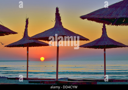 Sunrise unter Sonnenschirm am schwarzen Meeresstrand Stockfoto