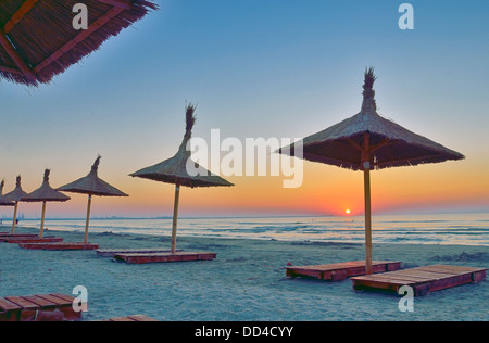 Sunrise unter Sonnenschirm am schwarzen Meeresstrand Stockfoto