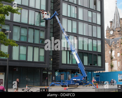 Fensterreiniger mit einem hydraulischen Lift oder Hubarbeitsbühne auf der Viertelmeile Entwicklung, mittlere Wiese gehen, Edinburgh, Schottland Stockfoto