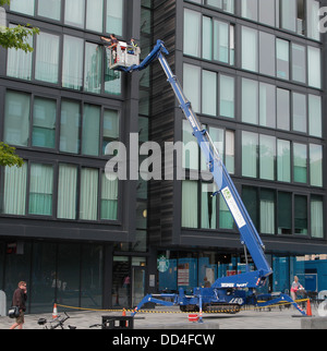 Fensterreiniger mit einem hydraulischen Lift oder Hubarbeitsbühne auf der Viertelmeile Entwicklung, mittlere Wiese gehen, Edinburgh, Schottland Stockfoto