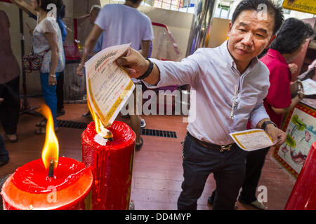 Bangkok, Thailand. 26. August 2013. Ein Mann brennt die Quittung erhielt er nach einem Sarg an den Poh Teck Tung Foundation für Hungry Ghost Monat in Bangkok zu spenden. Brennen die Quittung, die eine Form von Ghost Geld ist, ist ein Teil des Rituals der Spenden Särge. Poh Teck Tung betreibt Krankenhäuser und Schulen und bietet Unterstützung für die Armen in Thailand. Die siebten Mondmonats (August - September 2013) ist, wenn die chinesische Gemeinschaft glaubt, dass die Hölle Tor öffnet sich um Geister in der menschlichen Welt für einen Monat frei herumlaufen zu lassen. Stockfoto