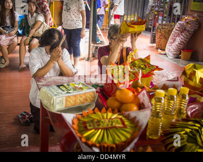 Bangkok, Thailand. 26. August 2013. Frauen beten vor der Spende Grundnahrungsmitteln der Poh Teck Tung Foundation für Hungry Ghost Monat in Bangkok. Poh Teck Tung betreibt Krankenhäuser und Schulen und bietet Unterstützung für die Armen in Thailand. Die siebten Mondmonats (August - September 2013) ist, wenn die chinesische Gemeinschaft glaubt, dass die Hölle Tor öffnet sich um Geister in der menschlichen Welt für einen Monat frei herumlaufen zu lassen. Viele Haushalte und Tempeln hält Gebetszeremonien während der einmonatigen Hungry Ghost Festival (Phor Thor) um die Geister zu besänftigen. Stockfoto