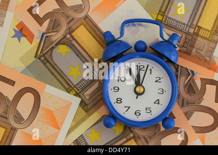 Zeit ist Geld-Konzept, Miniatur Uhr auf Banknoten Stockfoto