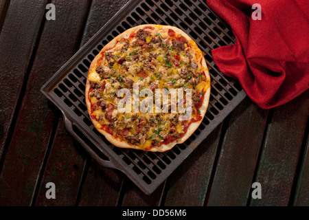 Cheeseburger-Pizza mit Cheddar-Käse, Boden Roastbeef und würzige Gurken, servierfertig. Stockfoto