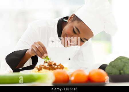 schöne afrikanische Köchin Spaghetti Gericht garnieren Stockfoto