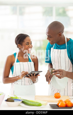 lächelnd African Paar auf der Suche nach einem Rezept mit Tablet-PC Stockfoto