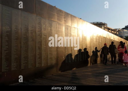 Eine Familiengruppe zu Fuß neben der Willkommen Wand am Darling Harbour, Sydney, Australien, in der späten Nachmittagssonne Schatten gießen Stockfoto