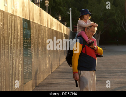 Ein Großvater trägt seiner Enkelin auf seiner Schulter, Stand sie neben der Willkommen Wand am Darling Harbour, Sydney Stockfoto