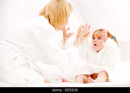 glückliche junge Mutter mit Tochter am Bett zu Hause spielen Stockfoto