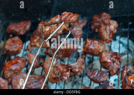 Fleisch am Grill, ein Stück Fleisch in Zangen. Closeup. Stockfoto