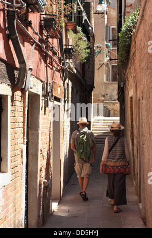 Touristen zu Fuß entlang einer schmalen Straße in Venedig. Stockfoto