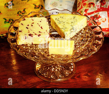 Blue Stilton, Wensleydale mit Preiselbeeren und Cheddar-Käse auf einer Glasplatte mit Weihnachtsgeschenke nach hinten stehen. Stockfoto