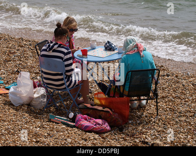 Drei Frauen spielen Scrabble am Strand, Milford am Meer, Dorset, UK 2013 Stockfoto