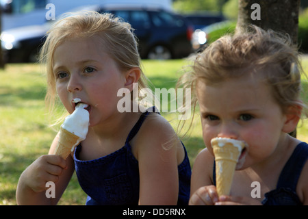 Schwestern, essen Eis Sahne Kegel im Schatten eines Baumes Stockfoto