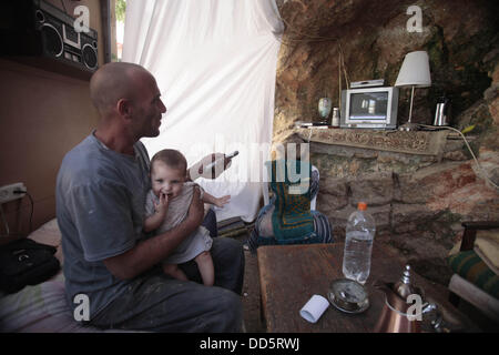 Silwan, Jerusalem, Palästina. 26. August 2013. Khaled al-Zeer al-Husaini, 39, schaut TV in seiner Höhle im Osten Jerusalems arabische Viertel Silwan, 26. August 2013. Al-Husaini ist Vater von fünf Kinder Leben in einer Höhle, das war ein Stall für die Tiere, nach israelische Behörden seinen eigenen vier Wänden unter dem Vorwand der Gebäude ohne Genehmigung Kredit vor 3 Tagen abgerissen: Saeed Qaq/APA Images/ZUMAPRESS.com/Alamy Live News Stockfoto